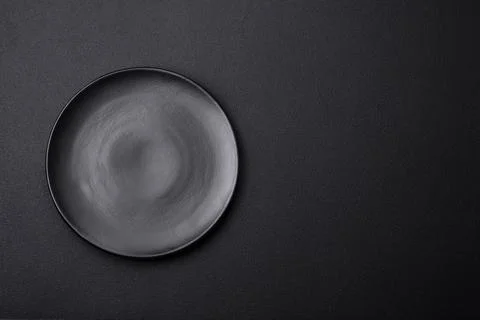 Empty ceramic round plate on dark textured concrete background Stock Photos