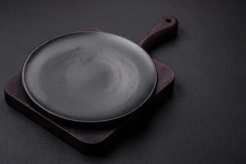 Empty ceramic round plate on dark textured concrete background Stock Photos