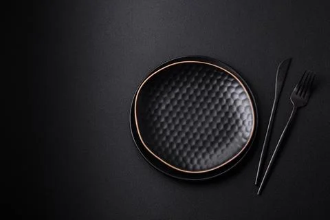 Empty ceramic round plate on dark textured concrete background Stock Photos