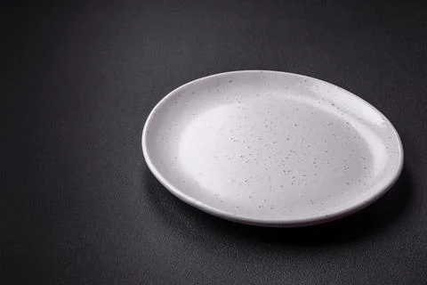 Empty ceramic round plate on dark textured concrete background Stock Photos