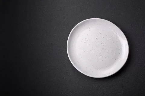 Empty ceramic round plate on dark textured concrete background Stock Photos