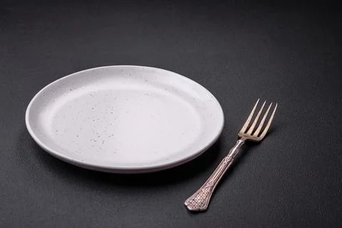 Empty ceramic round plate on dark textured concrete background Stock Photos