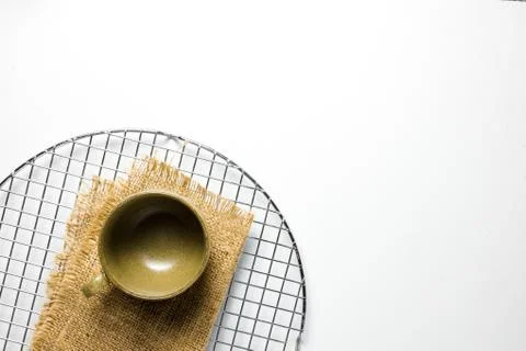 An empty ceramic teacup is photographed with a burlap pad on a cake dryer net Foto stock