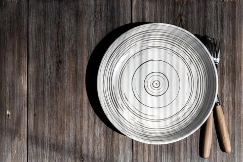 Empty ceramic white plate on a rustic loft wooden table. Kitchen food background Stock Photos