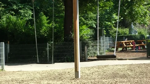 Empty chain swing moving slowly in playground on sunny summer day Stock Footage 341266145