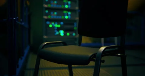 Empty chair in a dimly lit server room with glowing lights at night Stock Footage 309610720