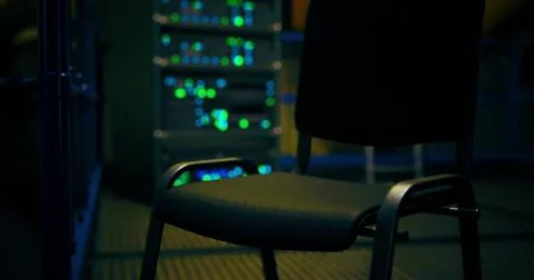 Empty chair in a dimly lit server room with glowing lights at night Stock Illustration
