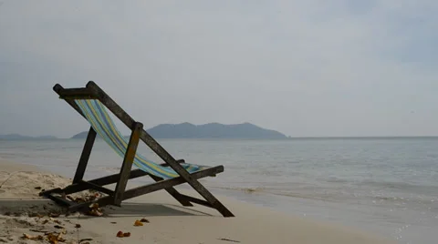 An empty chair on a sandy beach near the water Stock Footage 34365850