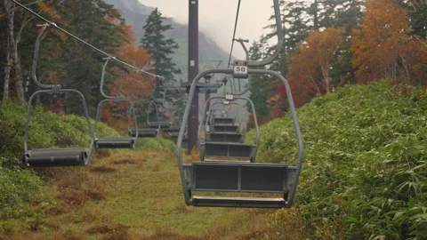 Empty chairlift moving up the mountain during autumn season in Daisetsuzan Stock Footage 340667906