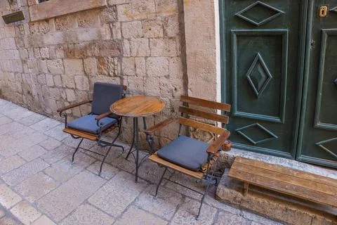 Empty chairs and table on the stone street of medieval town Stock Photos