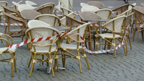 Empty chairs and tables of a cafe , barrier tape, coronavirus , closed, Breme Stock Footage 154448566