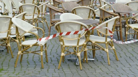 Empty chairs and tables of a cafe , barrier tape, coronavirus , closed, Breme Stock Footage 154448583