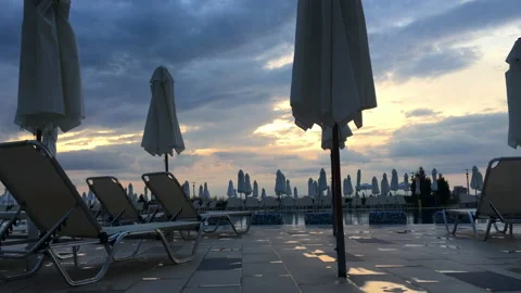 Empty chairs and umbrellas around outdoor swimming pool in hotel resort Stock Footage 137903584