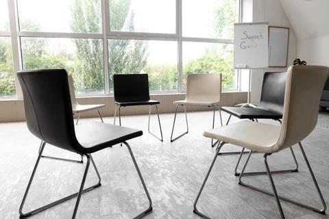 Empty chairs arranged in a circle for support group meeting Stock Photos