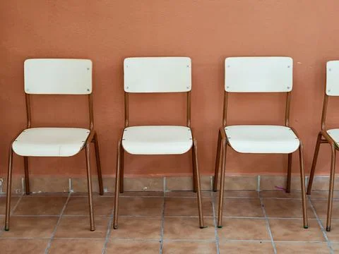 Empty chairs lining wall symbolizing waiting and anticipation Stock Photos