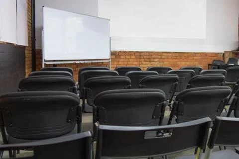Empty chairs rows in front of white board and wall display before presentatio 스톡 사진