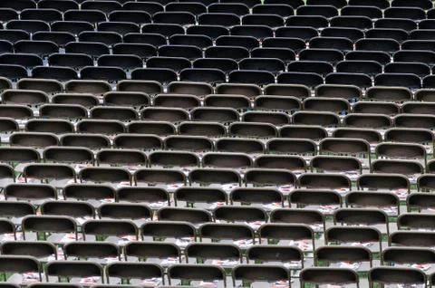 Empty chairs in a stadium, lined-up waiting for people to take their seat. Stock Photos
