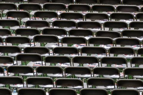 Empty chairs in a stadium, lined-up waiting for people to take their seat. Stock Photos