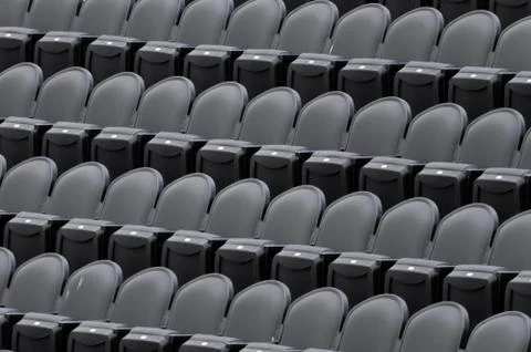 Empty chairs in a stadium, lined-up waiting for people to take their seat. Stock Photos