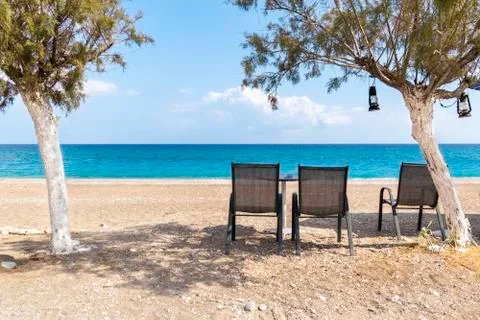 Empty chairs under tree with view of sea on Afandou beach near Faliraki (Rhod Stock Photos