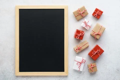Empty chalkboard and gift boxes on light gray background. Stock Photos