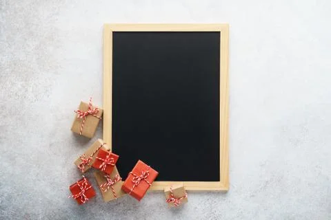 Empty chalkboard and gift boxes on light gray background. Stock Photos