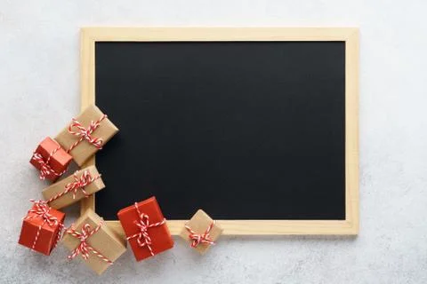 Empty chalkboard and gift boxes on light gray background. Stockfoto's
