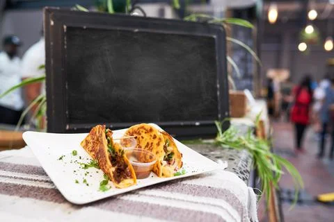 An empty chalkboard at a market with soft shell tacos in foreground - copy space Stock Photos