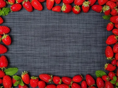 Empty chalkboard surrounded by red strawberries and green leaves Stock Photos