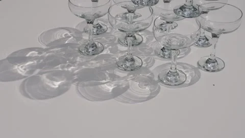 Empty champagne coupe glasses arranged on white table with shadows Stock Footage 337578093