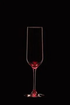 Empty champagne flute backlit with red light and isolated on black background. Stock Photos