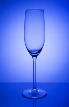 Empty champagne glass on a mirror with spot in blue background Stock Photos