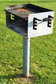An empty charcoal barbeque fire grill on a green field Stock Photos