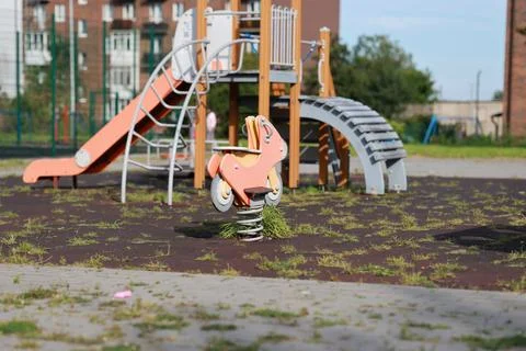 Empty children playground with spring rocker and slide in residential courtya Stock Photos