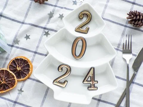 Empty christmas tree shaped white plate with 2024 on towel background Stock Photos