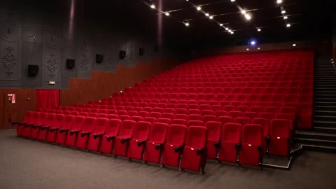 Empty cinema auditorium with rows of red velvet seats and ceiling lights Stock Footage 335780452