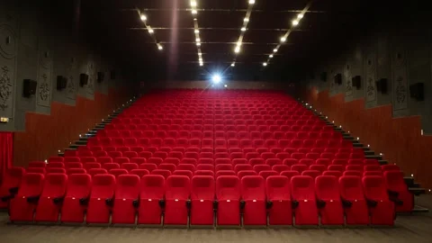 Empty cinema auditorium with rows of red velvet seats and ceiling lights Stock Footage 335780744