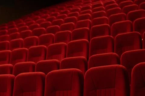 Empty cinema auditorium with rows of red velvet seats and ceiling lights Stock Photos