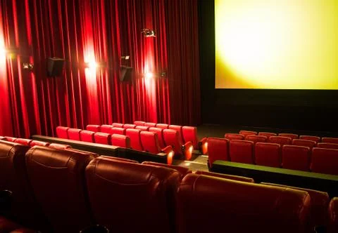 Empty cinema with blank screen and rows of red seats Stock Photos