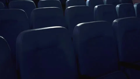 An empty cinema hall with rows of seats lit by the changing glow of the screen. 스톡 동영상 314197211