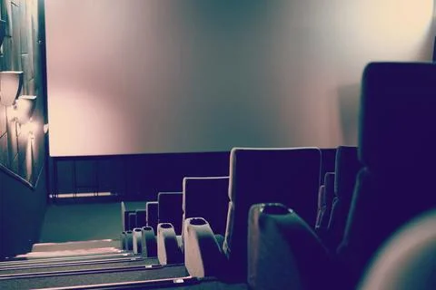 Empty cinema with white screen and seats. Side view Stock Photos