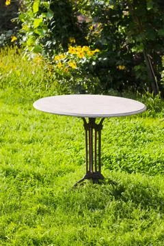 Empty circular marble table located on a very striking green grass Stock Photos
