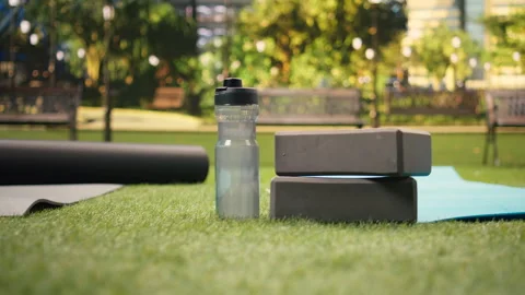 Empty city park space with water bottle and yoga bricks placed on grass Stock Footage 346028232