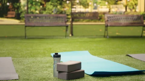 Empty city park space with water bottle and yoga bricks placed on grass Stock Footage 346032803