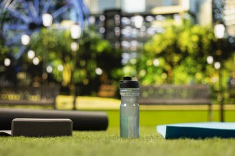 Empty city park space with water bottle and yoga bricks placed on grass near mat Stock Photos