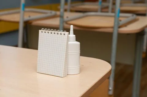 Empty classroom desk with notepad and glue bottle Stock Photos