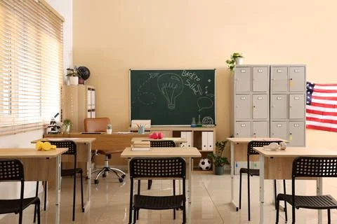 Empty classroom interior with desks, chairs, chalkboard, lockers, and america Stock Photos