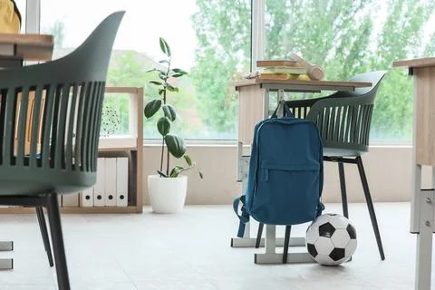 Empty classroom interior with student desk, backpack, books, and soccer ball, Stock Photos