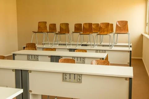Empty classroom with stacked chairs on desks and warm lighting ambiance Stock Photos