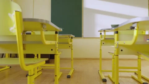 An empty classroom with yellow desks and a chalkboard in daylight appears clean Video stock 277932715